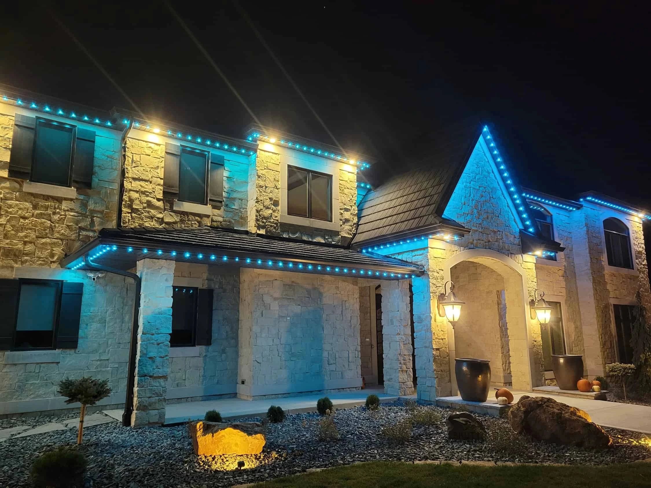 Stone two-story home in blue and white roofline lighting