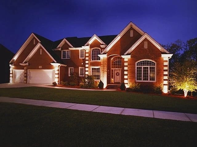 Large brick home with uplighting across the front facade
