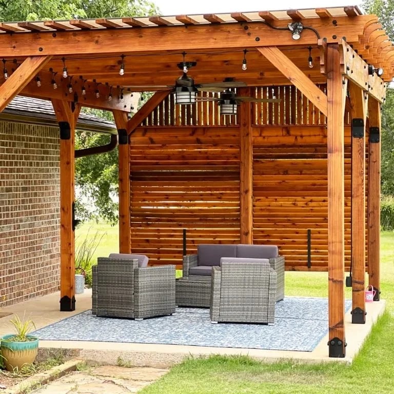Bronze pergola cover with a cedar privacy wall and patio seating