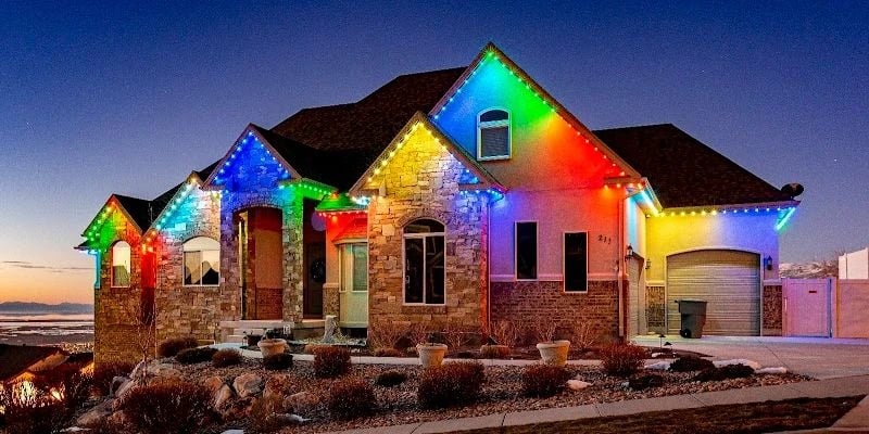 Home traced in multicolor roofline lighting at sunset