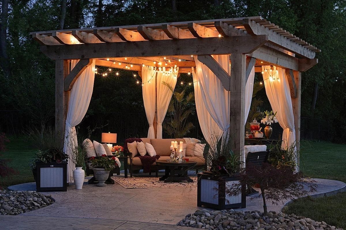 Pergola with curtains and string lights at dusk